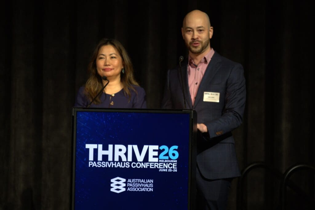 woman and man stand in front of a podium with "thrive26" logo